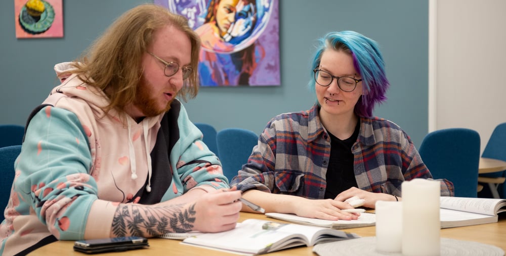 Två kursdeltagare sitter och studerar
