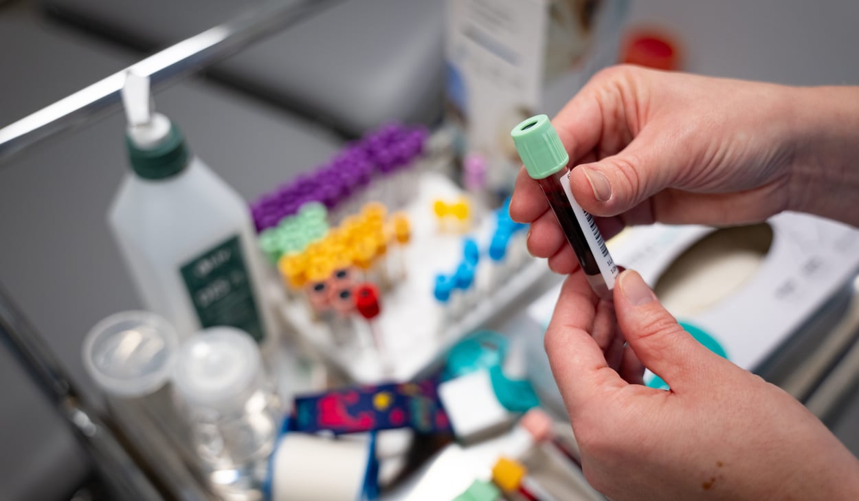 Händer som håller ett provrör med blodprov