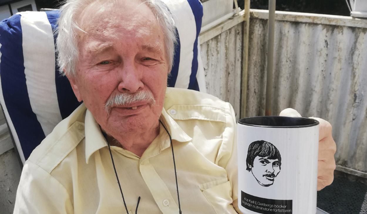 En man som sitter i en stol och håller i en kaffekopp.