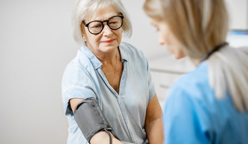 En kvinna med blodtrycksmätare runt armen.