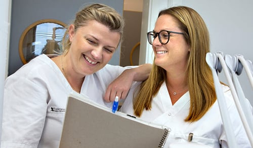 Två medarbetare från Folktandvården med ett anteckningsblock.