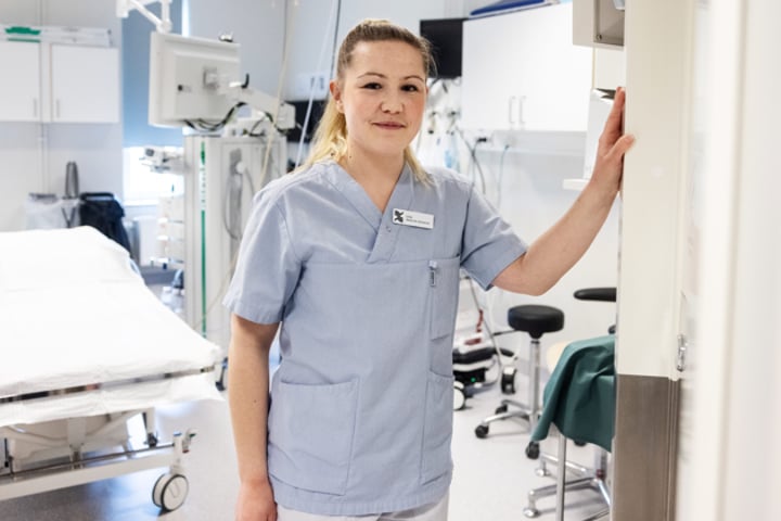 En kvinna i operationskläder står i ett sjukhusrum.